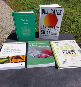 Zdjęcie przedstawia stolik w parku, a na nim rozłożone książki o tematyce ekologicznej.