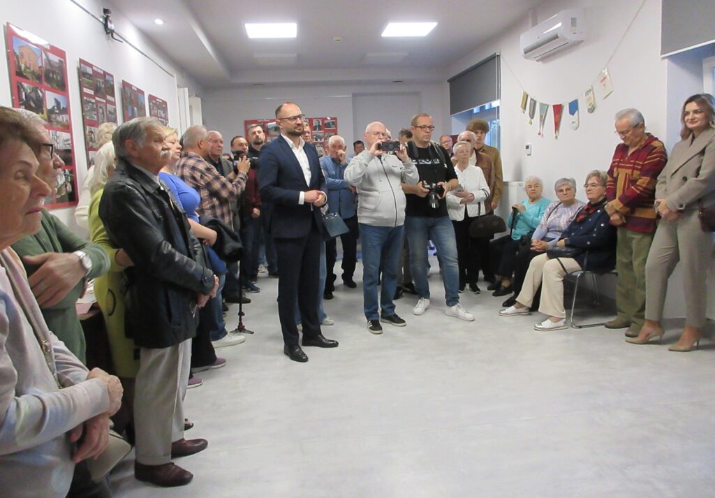 Na zdjęciu widoczna grupa ludzi zgromadzonych w sali wystawowej.