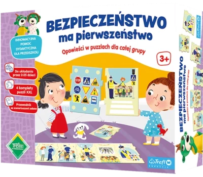 Zdjęcie okładki pudełka gry "Bezpieczeństwo ma pierwszeństwo". Na pierwszym planie dwie dziewczynki trzymające plansze z zasadami ruchu drogowego. U góry nazwa gry. po lewej stronie informacje dotyczące gry.