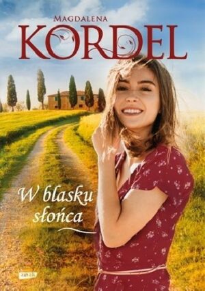 Zdjęcie okładki książki "W blasku słońca". Na pierwszym planie uśmiechnięta kobieta w bordowej sukience stojąca na polnej drodze w tle budynek za drzewami.