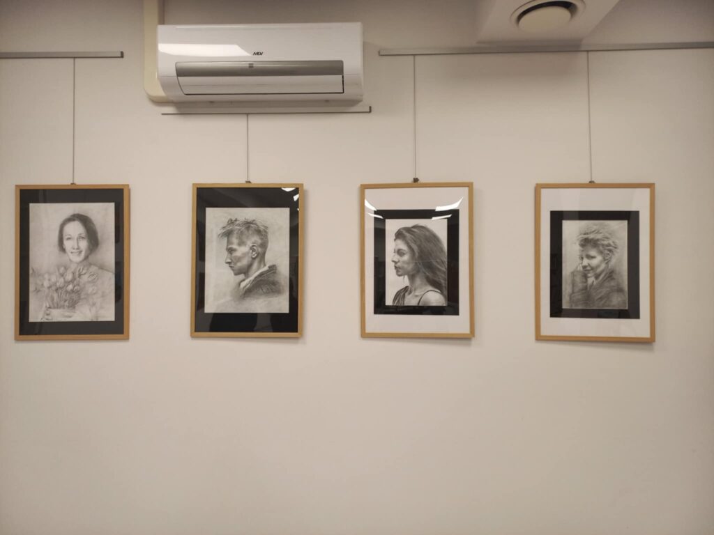Na zdjęciu widać cztery portrety w jasnych ramkach wiszące na ścianie.
