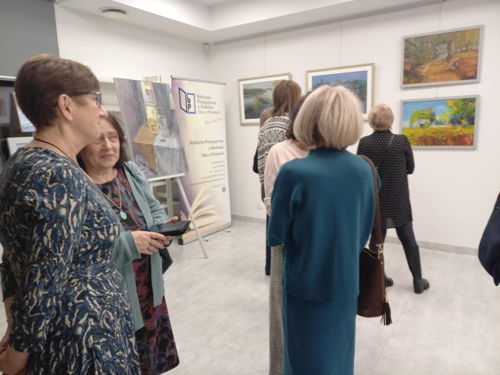 Na zdjęciu widoczne osoby zgromadzone w sali, oglądające obrazy.